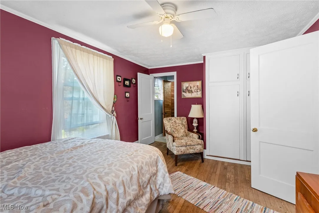 Bedroom featuring wood finished floors, ceiling fan, crown molding, and a closet