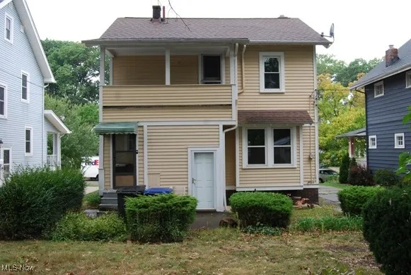 Rear view of house featuring a chimney, a balcony, and a shingled roof