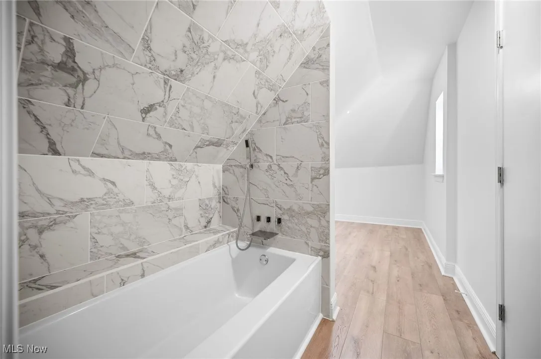 Full bath featuring vaulted ceiling, light vinyl floors, and shower / bath combination