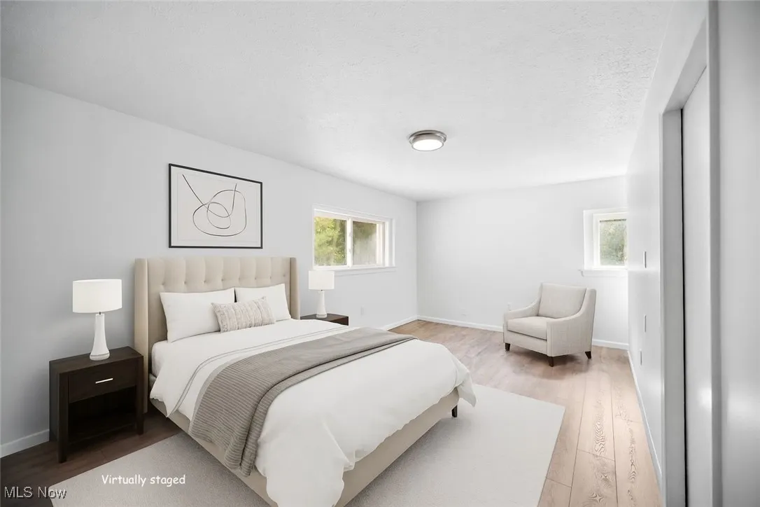 Virtually staged. Bedroom featuring light hardwood floors and a textured ceiling