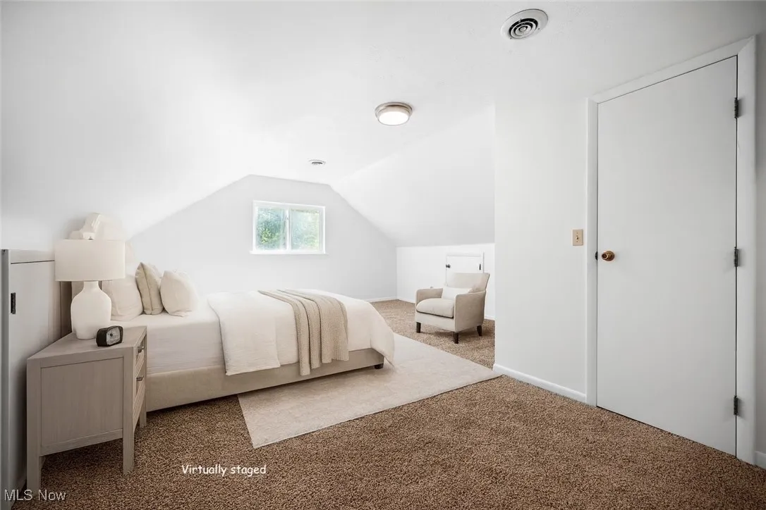 Virtually staged. Carpeted bedroom with lofted ceiling
