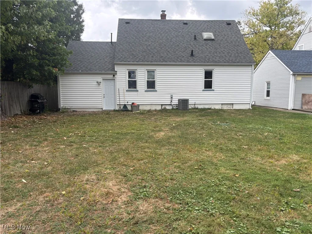 Back of property with a shingled roof and a chimney