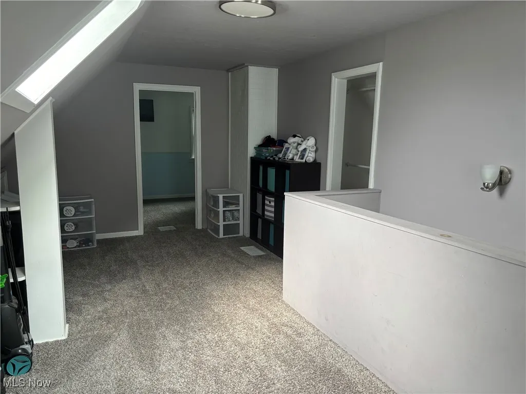 Loft light carpet, a skylight, and lofted ceiling