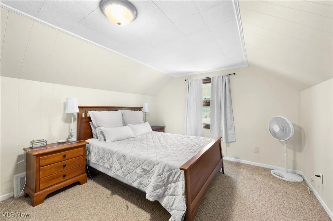 Bedroom featuring light carpet and vaulted ceiling