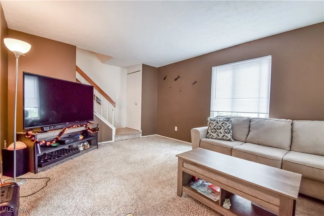 Carpeted living area with stairway and a textured ceiling