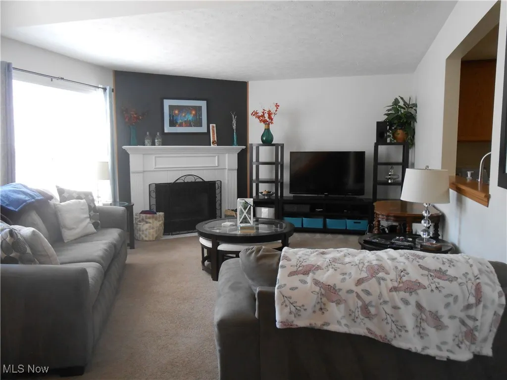 Carpeted living area with a fireplace and a textured ceiling