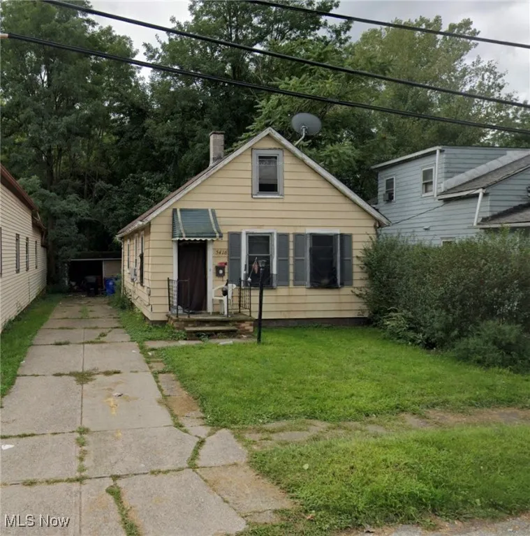 Bungalow-style home with a chimney, a front yard, and driveway