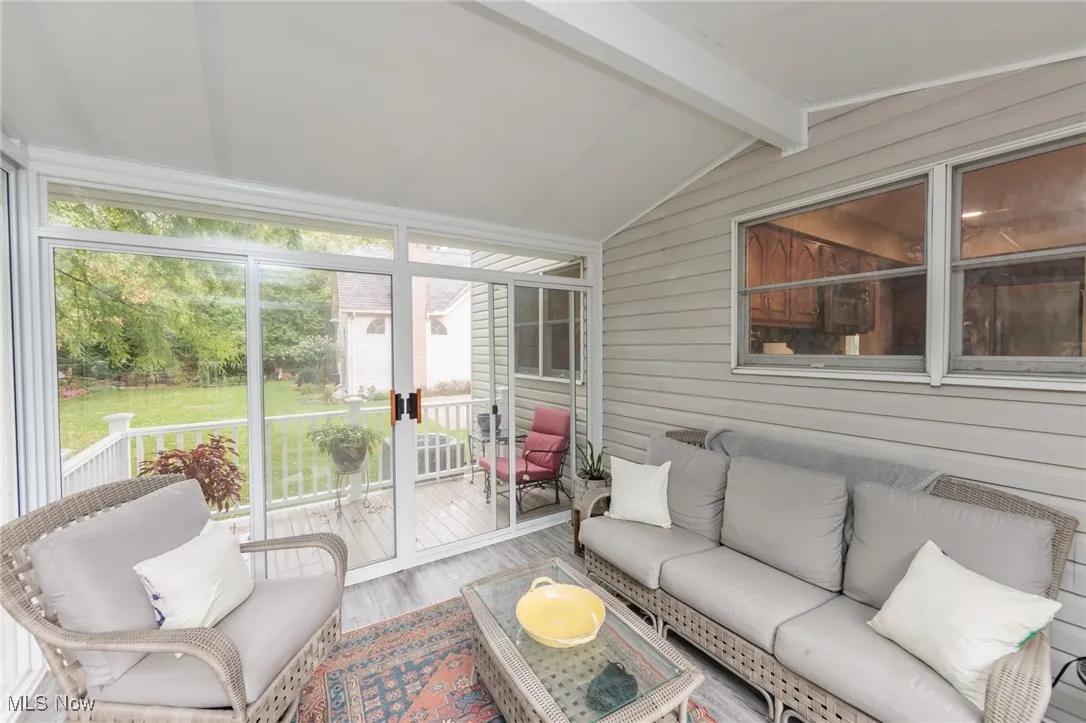 Sunroom / solarium with a deck and view of wooded green space.