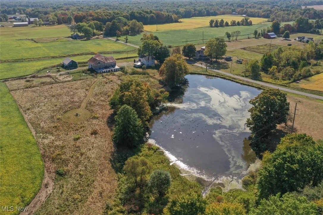 Aerial view of property and surrounding area featuring rural landscape and a large body of water