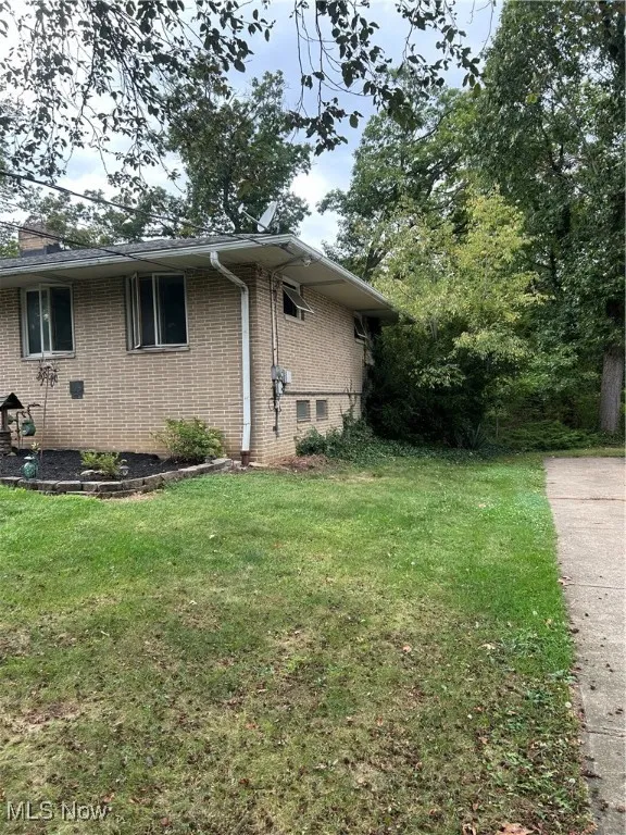 View of side of property with a lawn, brick siding, a chimney, and crawl space