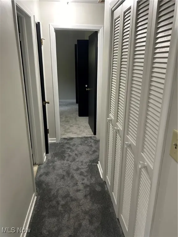 Hallway with dark carpet and baseboards
