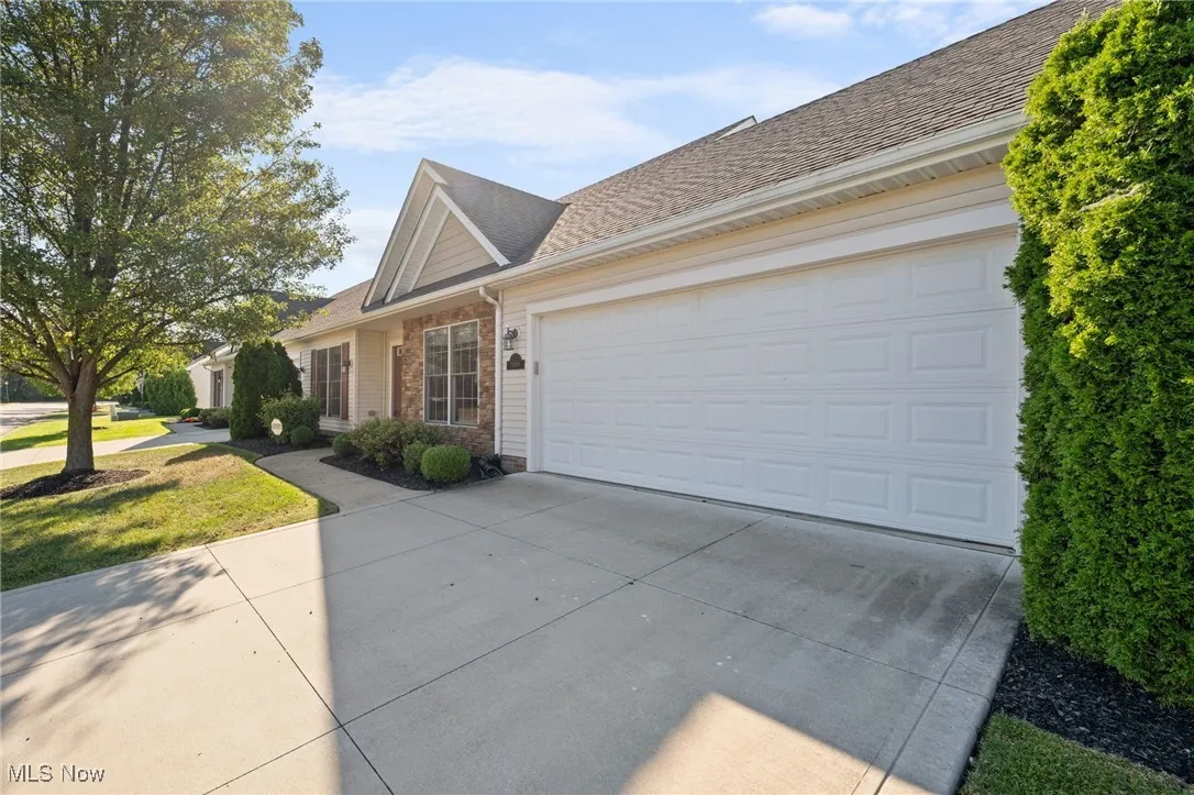 View of front facade featuring concrete driveway, roof with shingles, brick siding, an attached garage, and a front lawn
