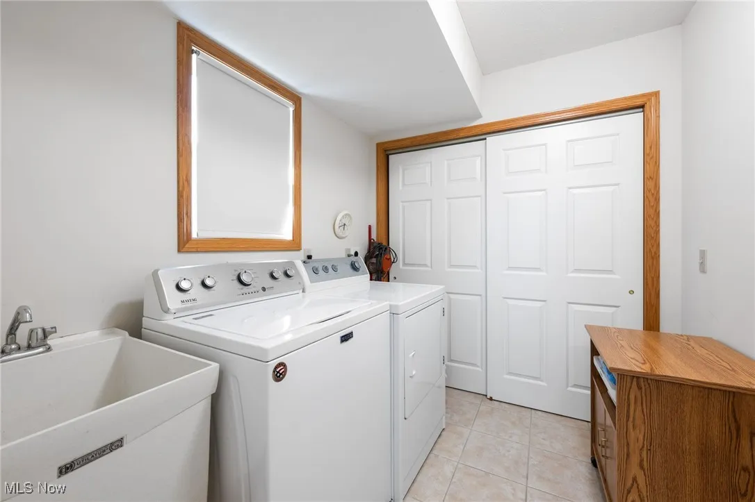 Washroom with washer and dryer and light tile patterned floors