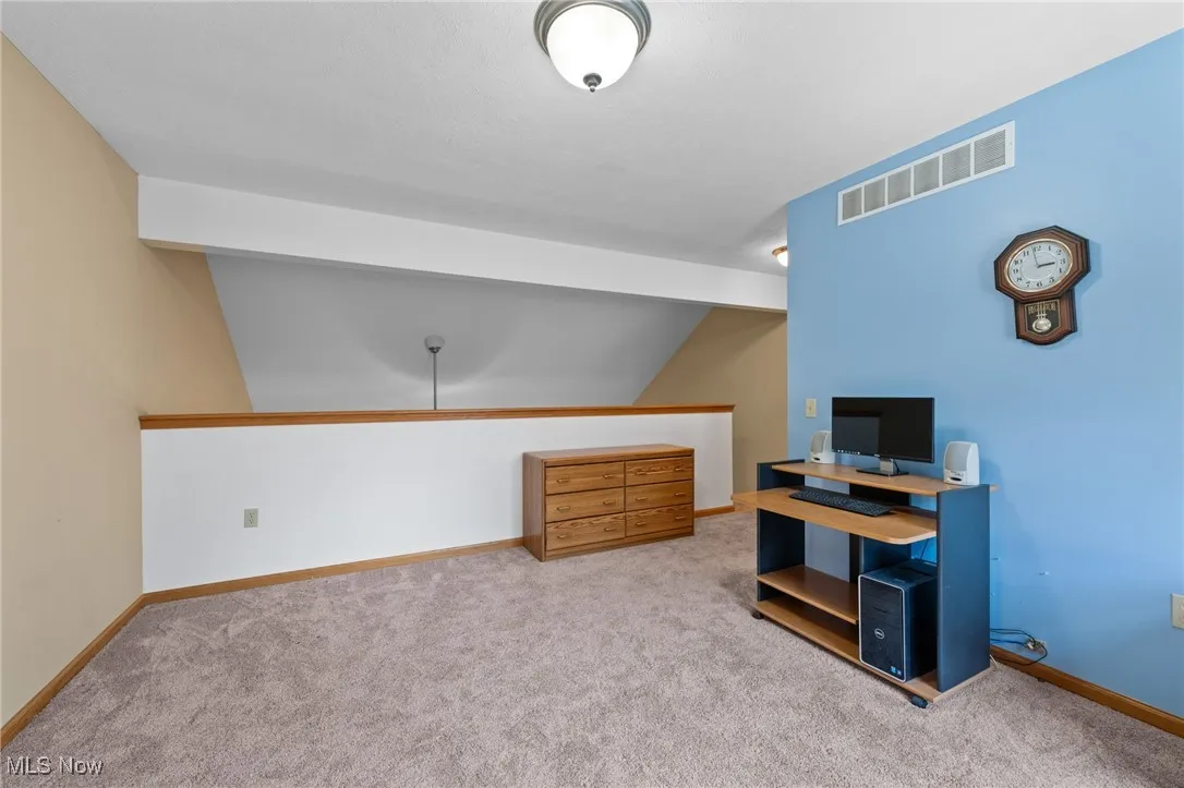 Carpeted office with baseboards and lofted ceiling