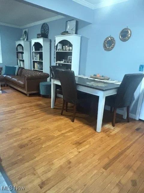Dining space with crown molding and light wood-type flooring
