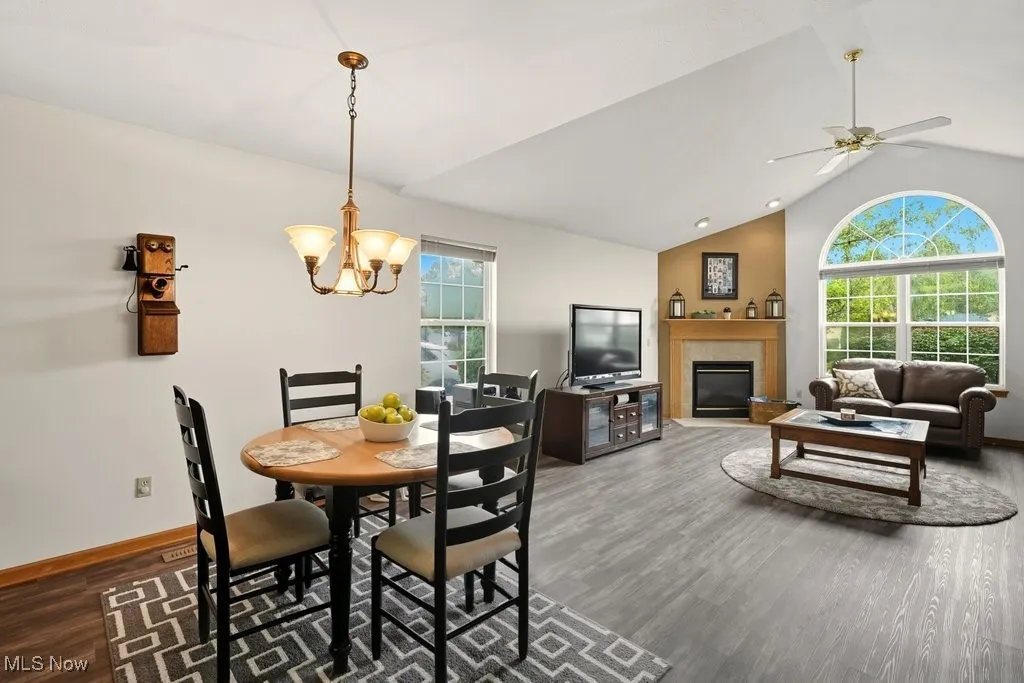 Dining room with a tile fireplace, vaulted ceiling, dark wood-style floors, and a chandelier