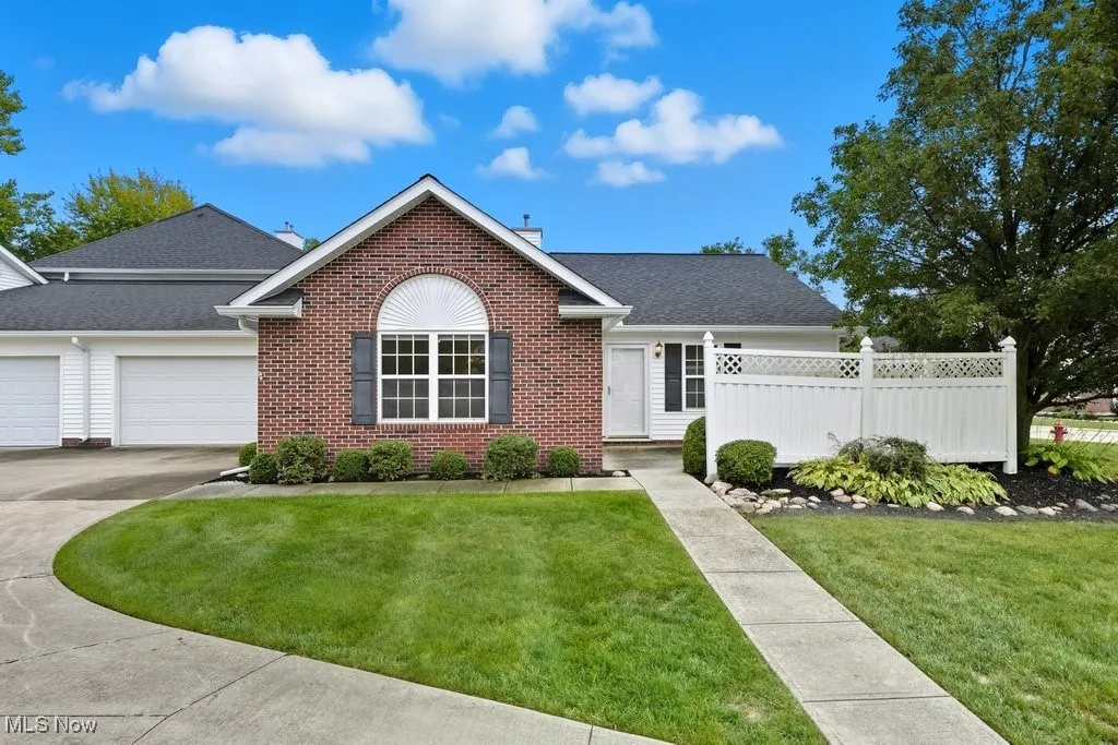Single story home with brick siding, a garage, and driveway