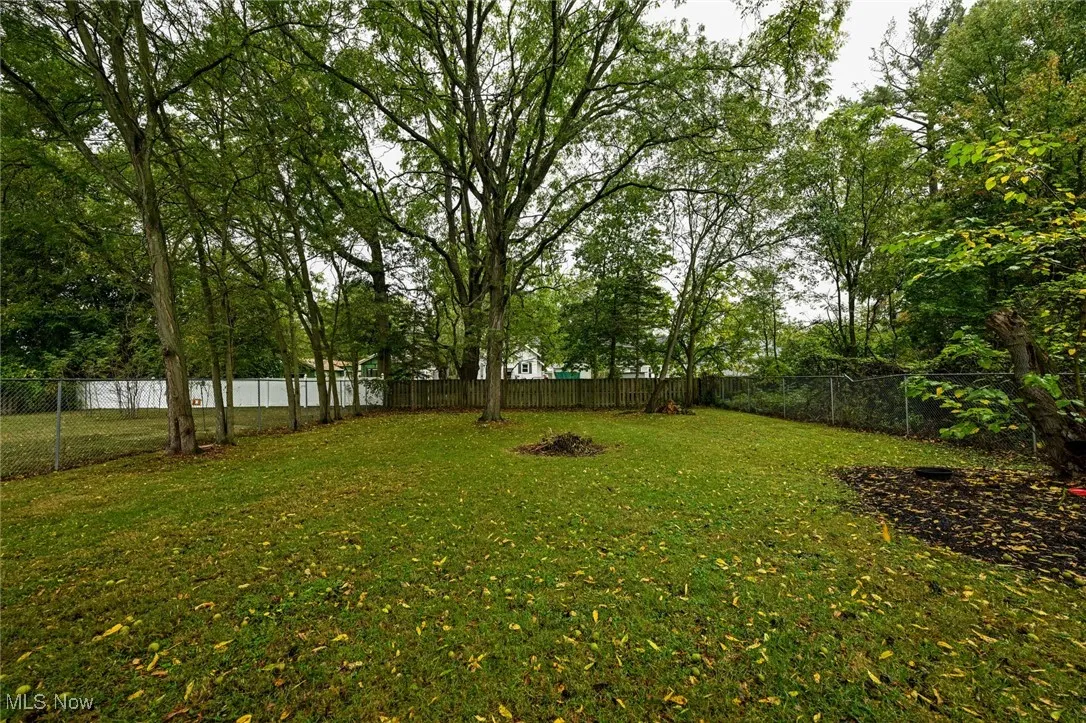 Fenced backyard with view of wooded area