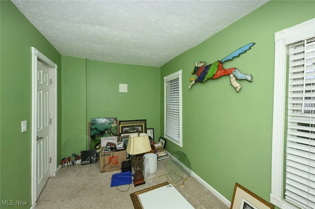 Carpeted office space with a textured ceiling and baseboards