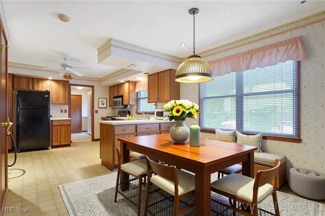 Dining room with wallpapered walls, ceiling fan, and ornamental molding