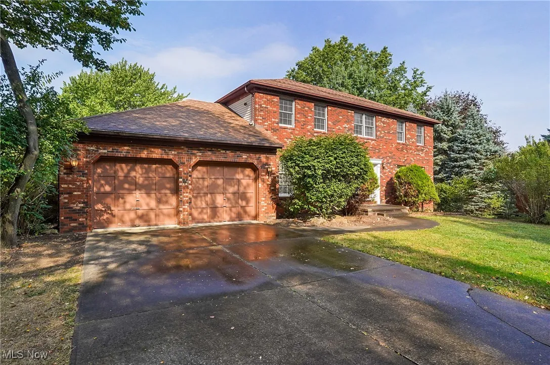 View of front of home with brick siding, driveway, an attached garage, and a front lawn