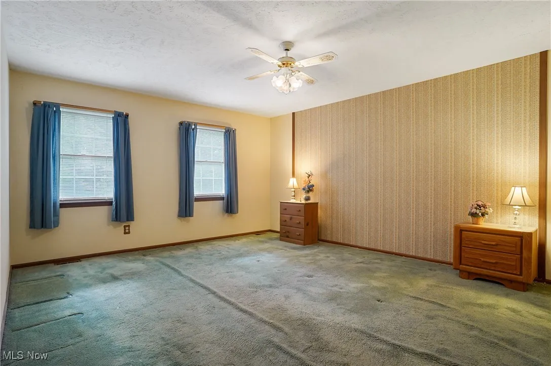 Unfurnished bedroom with a textured ceiling, a ceiling fan, carpet flooring, and wallpapered walls