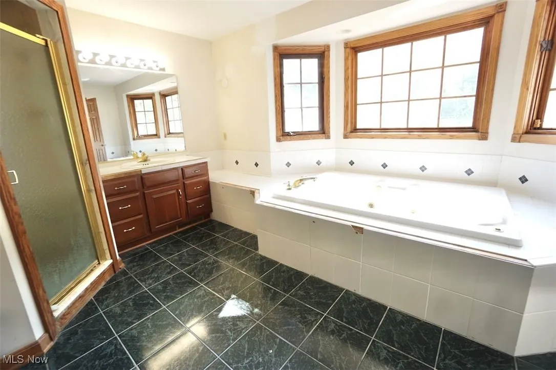 Master bathroom with vanity, a stall shower, a whirlpool tub, and dark tile patterned floors