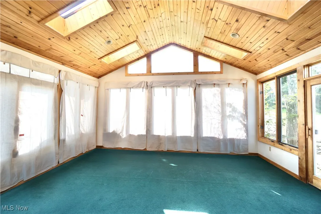 Spacious sun room with sky lights and entrance to rear patio.