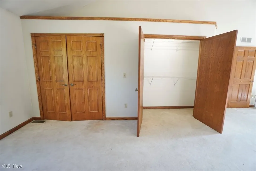 Primary bedroom with dual closets and light carpet