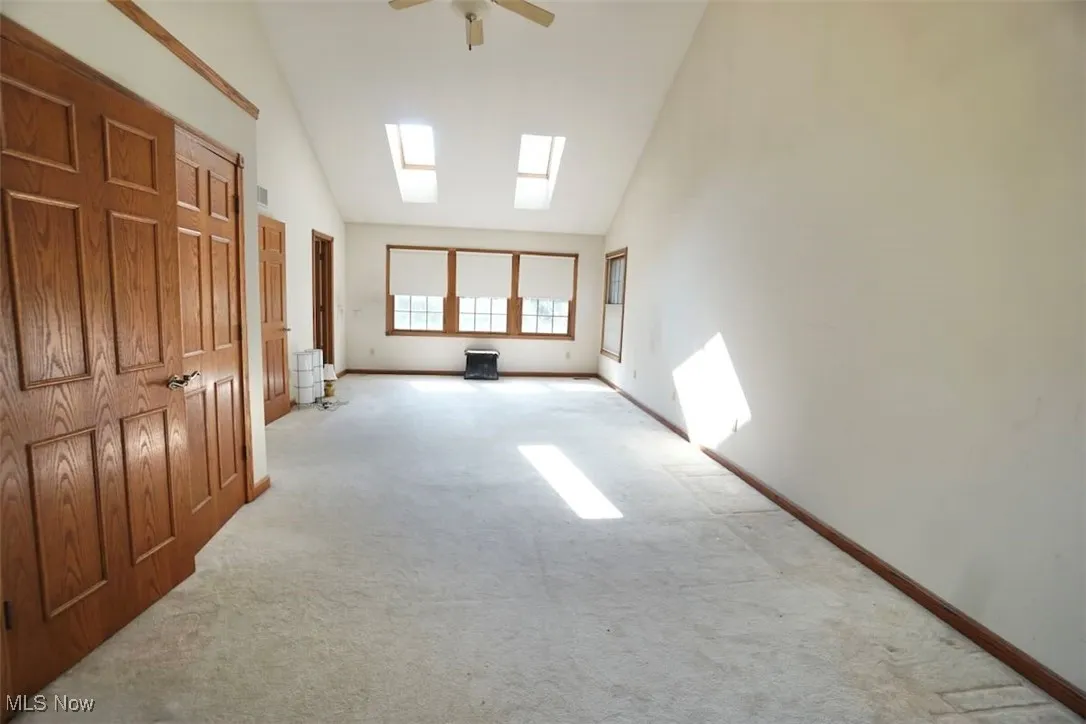 Master bedroom with carpet flooring, a skylight, high vaulted ceiling, and ceiling fan