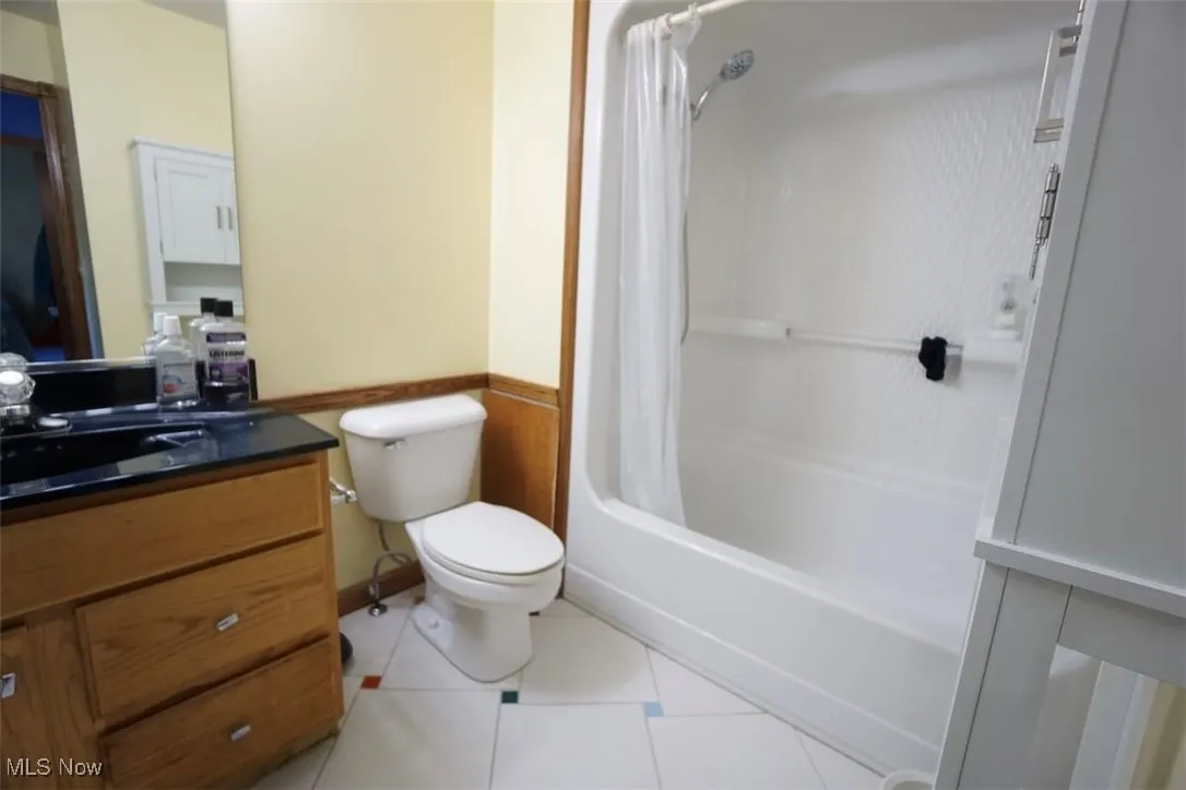 Bathroom with vanity, shower / tub combo, light tile patterned flooring.