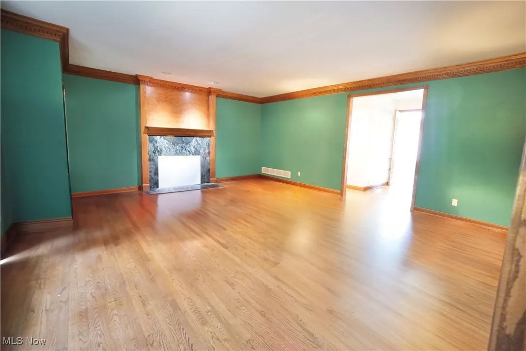 Unfurnished living room with crown molding, wood finished floors, and a fireplace
