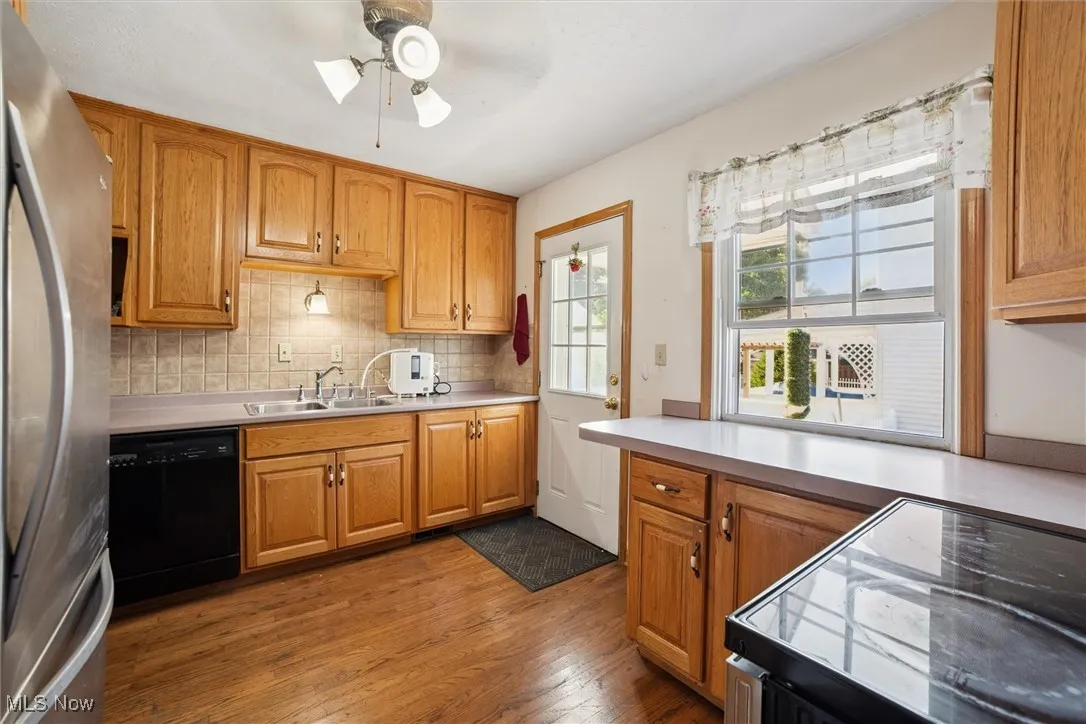 Kitchen featuring black appliances, backsplash, dark wood-type flooring, and brown cabinets