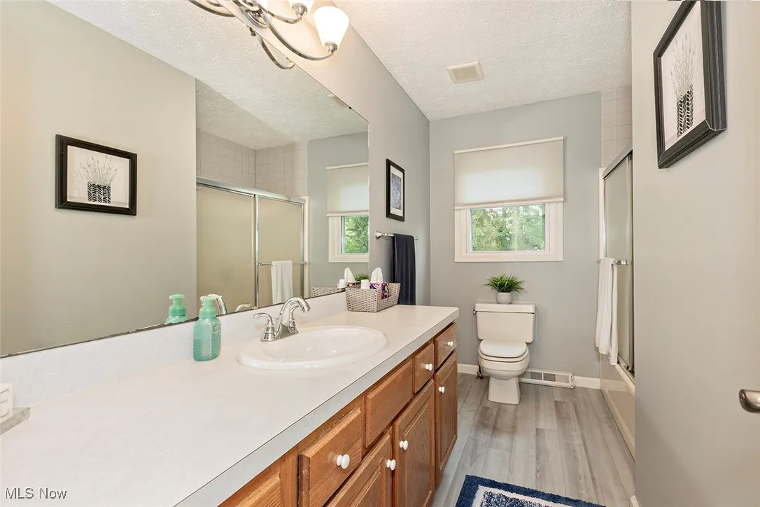 Full bath with a textured ceiling, vanity, and light wood-style floors