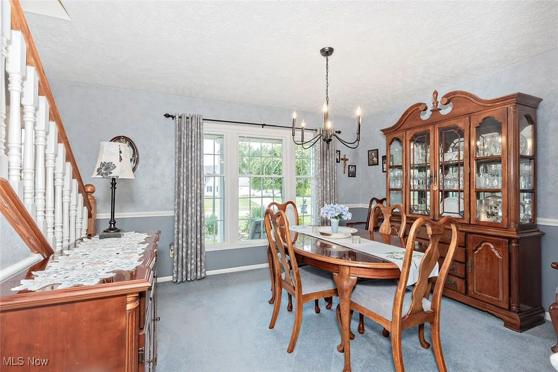 Dining area featuring carpet flooring, a chandelier, a textured ceiling, and stairway