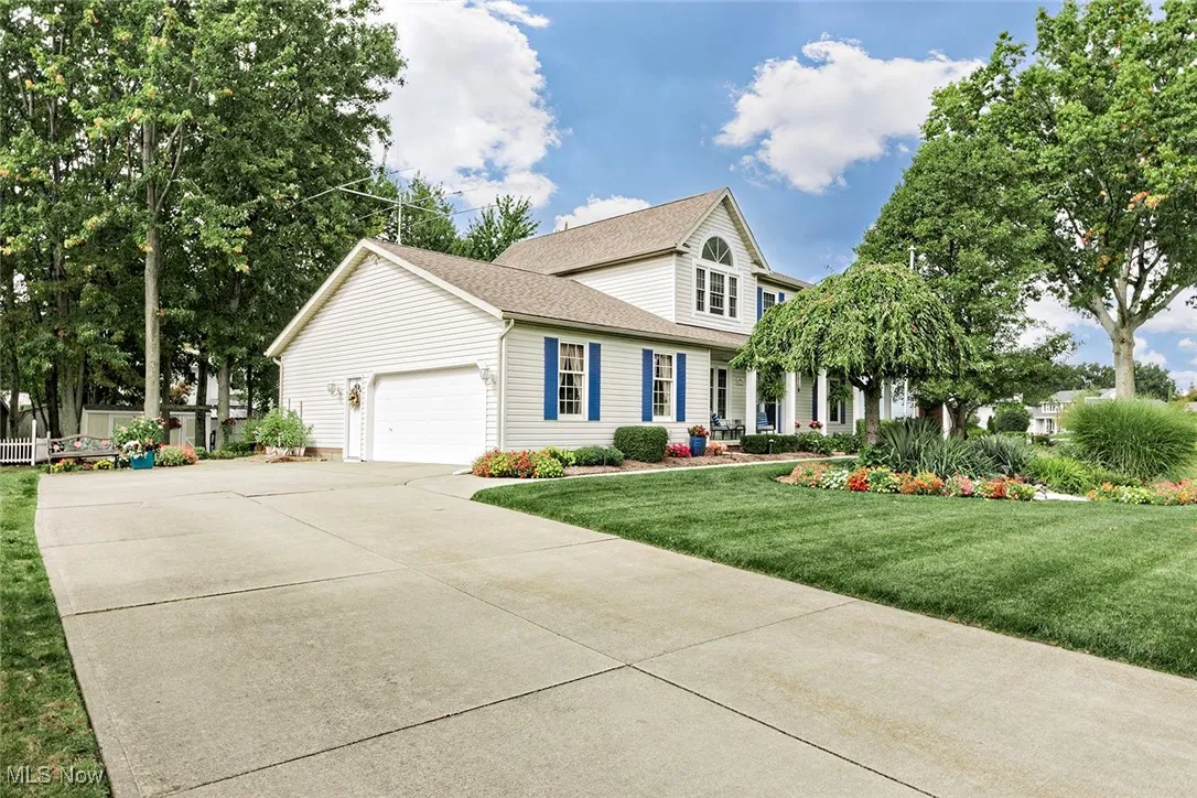 View of front of property featuring a front yard, driveway, an attached garage, and a shingled roof