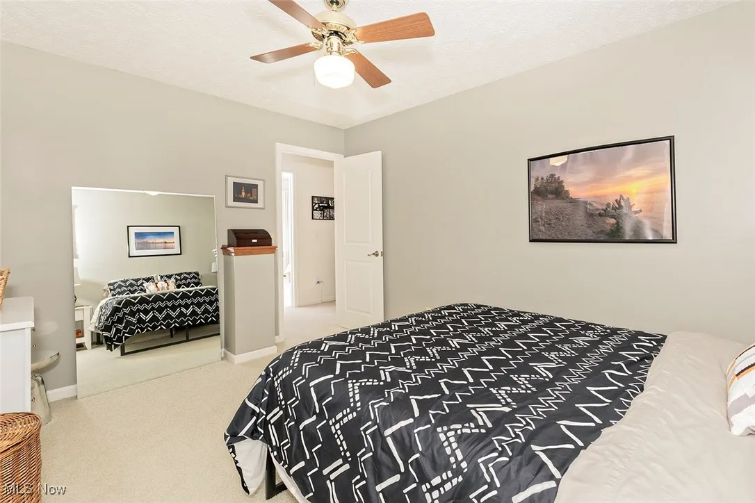 Bedroom with light carpet, a textured ceiling, and a ceiling fan