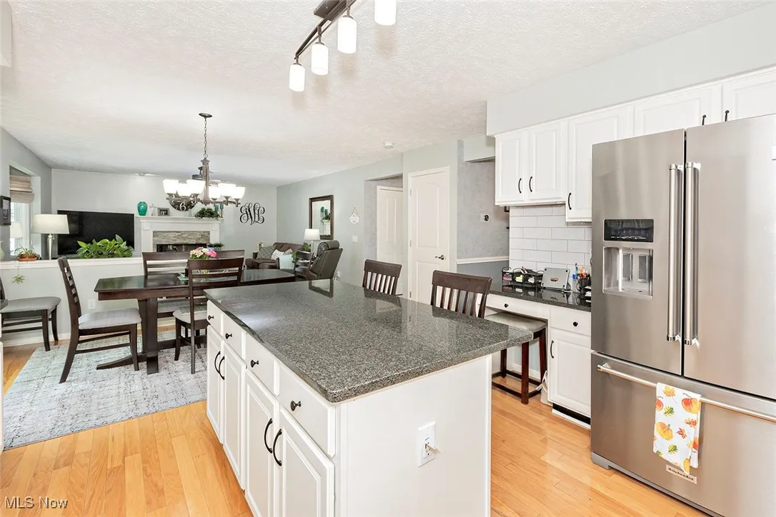 Kitchen featuring high end refrigerator, white cabinetry, a textured ceiling, light wood finished floors, and backsplash