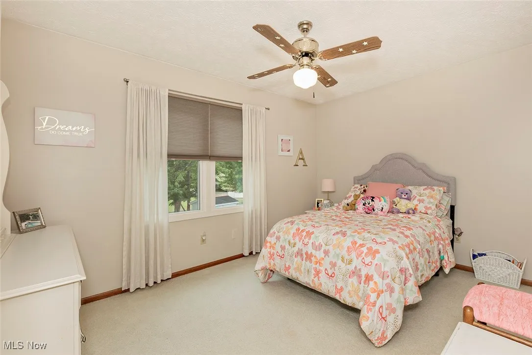 Carpeted bedroom featuring ceiling fan and a textured ceiling