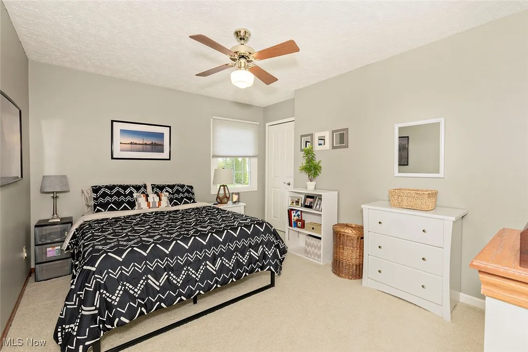 Bedroom featuring light colored carpet, a textured ceiling, and ceiling fan
