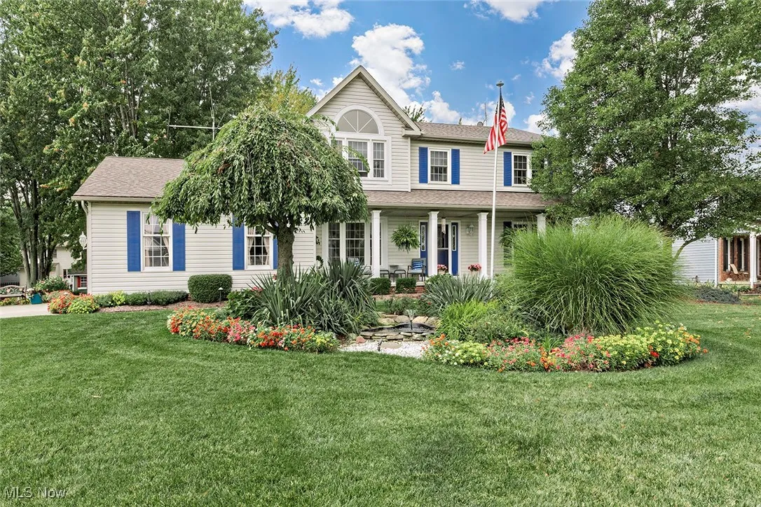 View of front of house with covered porch, a front lawn, and a shingled roof