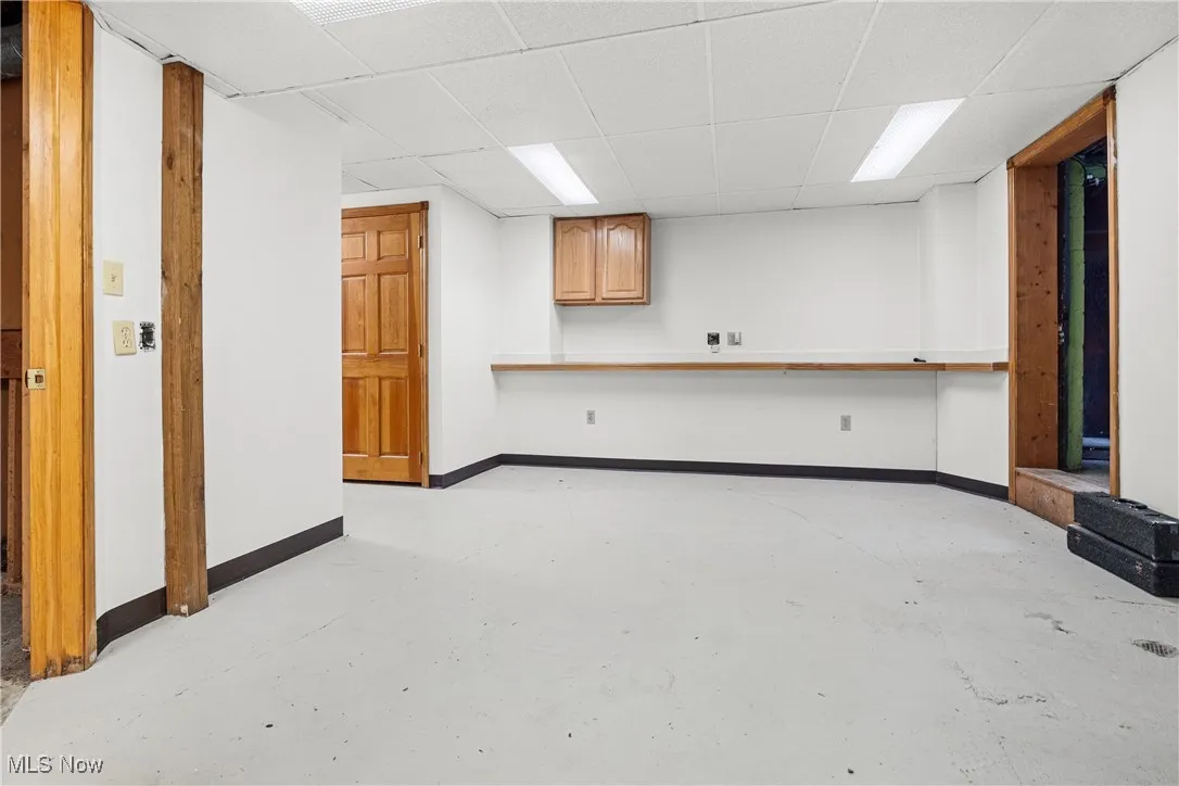 Unfurnished living room with a drop ceiling and concrete flooring