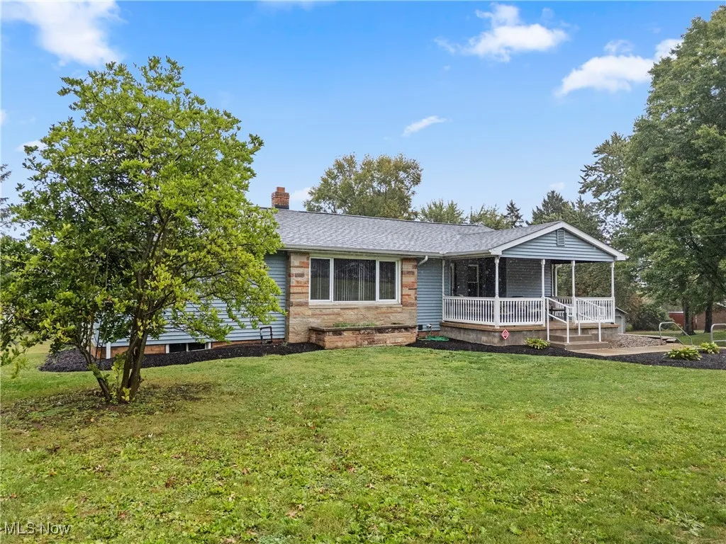 Single story home featuring a wooden deck, a front yard, a chimney, and a shingled roof