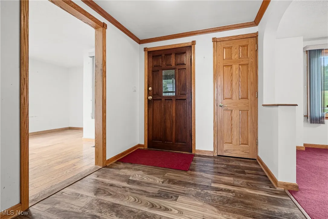 Entrance foyer featuring crown molding, dark wood finished floors, and plenty of natural light