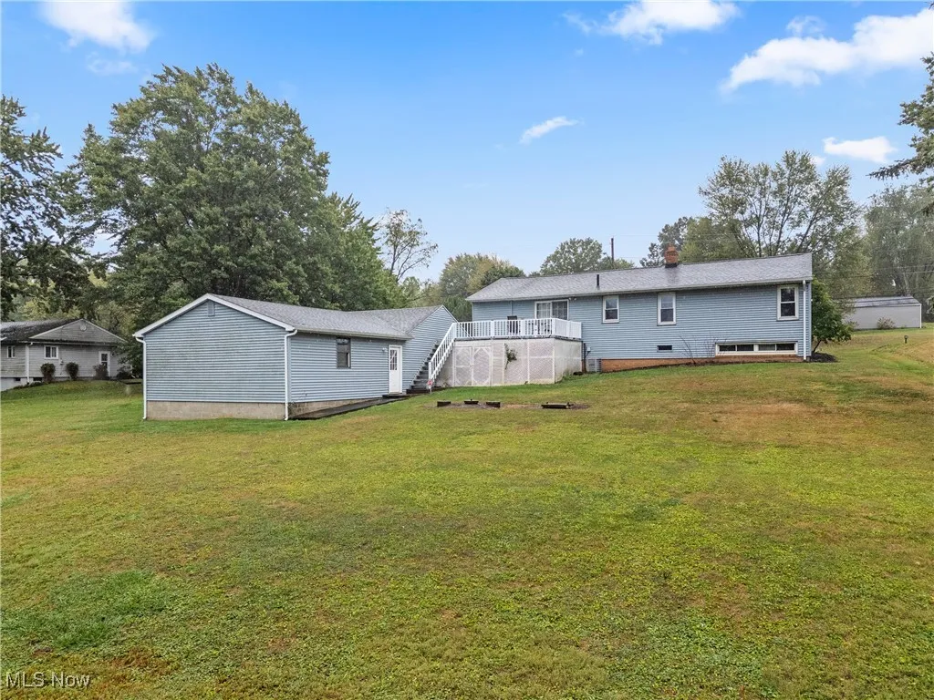 Rear view of house featuring a deck, a yard, stairway, and a chimney