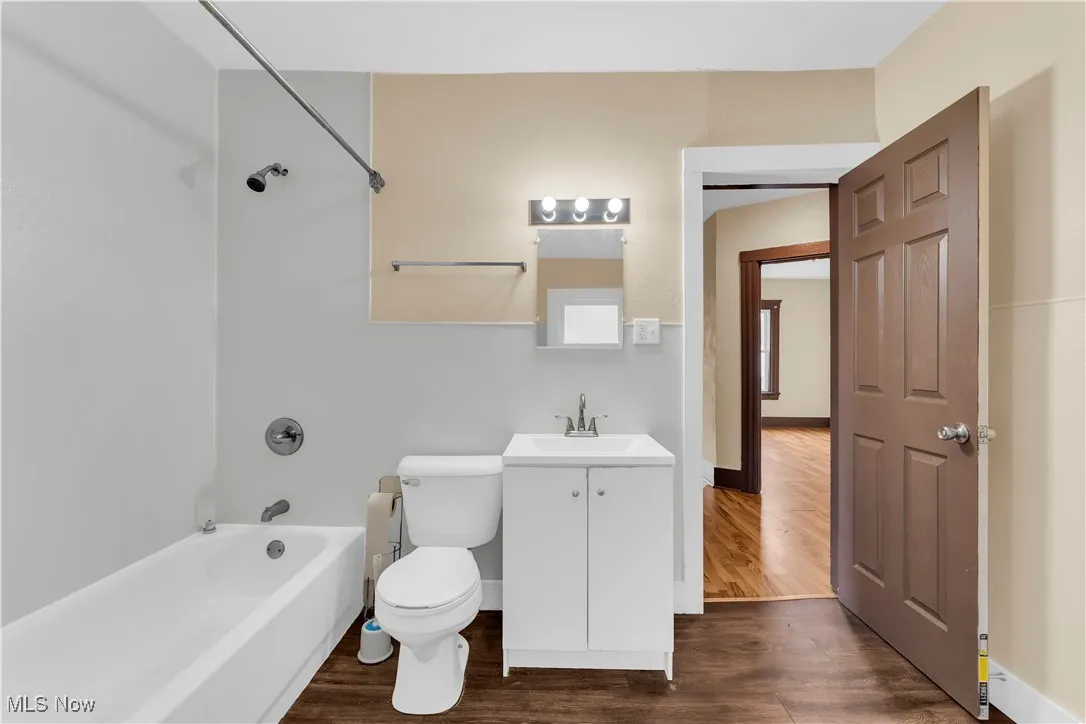 Bathroom with bathing tub / shower combination, dark wood finished floors, and vanity