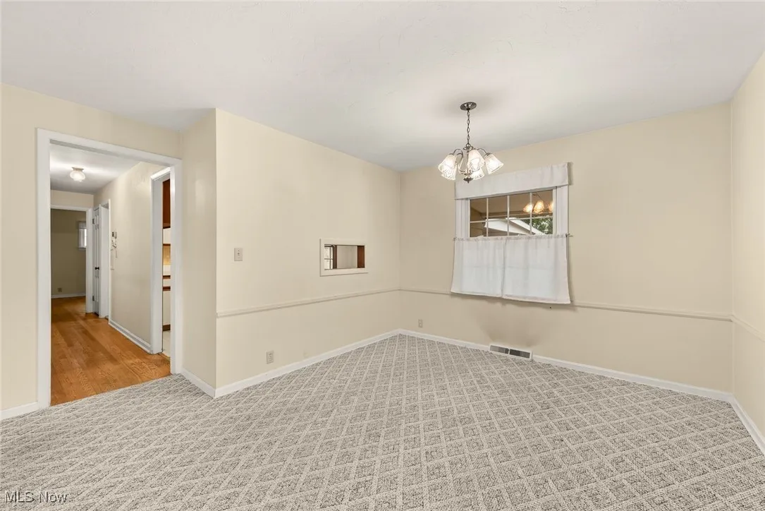 Unfurnished room with carpet flooring and a chandelier