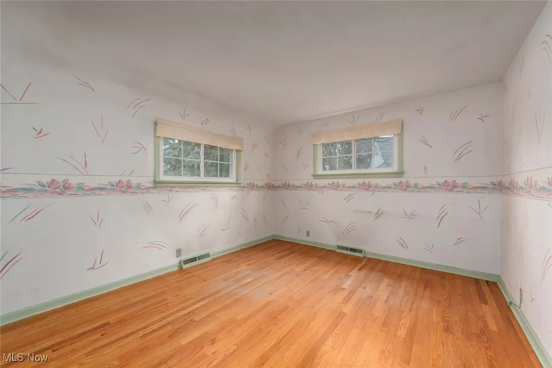 Empty room with light wood-style flooring and wallpapered walls