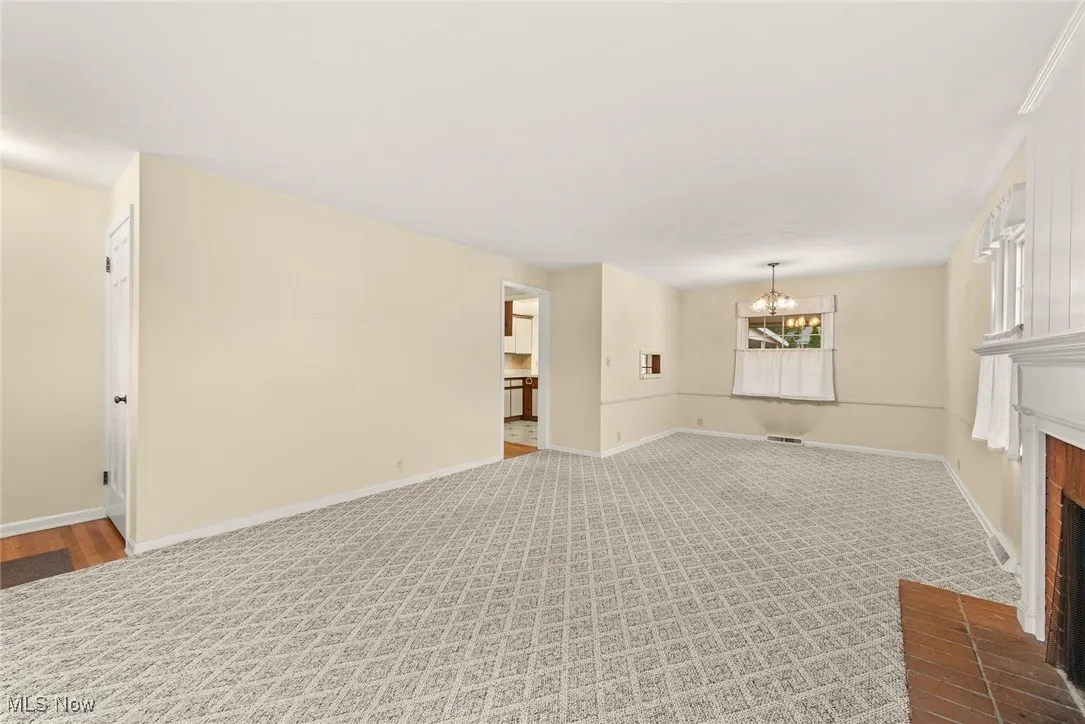 Unfurnished living room featuring a fireplace, carpet flooring, and a chandelier