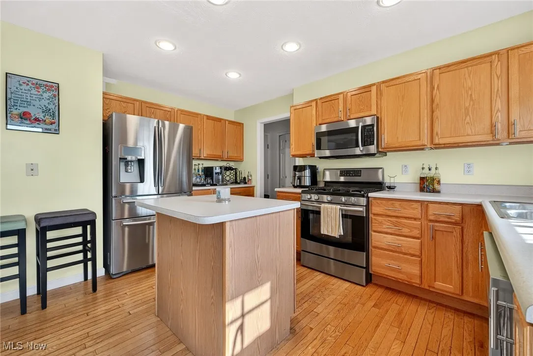 Kitchen featuring a kitchen island, stainless steel appliances, light wood finished floors, light countertops, and recessed lighting